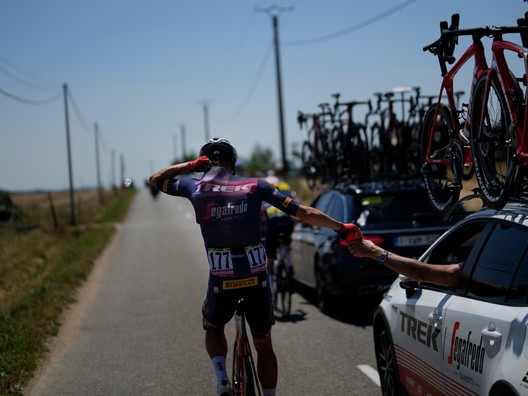 Tom Skujinš v 15. etape Tour de France berie fľaše s vodou z tímového auta a dáva si ich pod dres. 