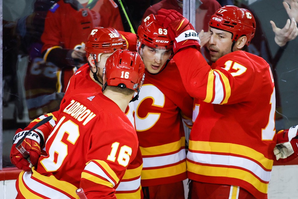 Adam Ružička oslavuje gól so spoluhráčmi v drese Calgary Flames.