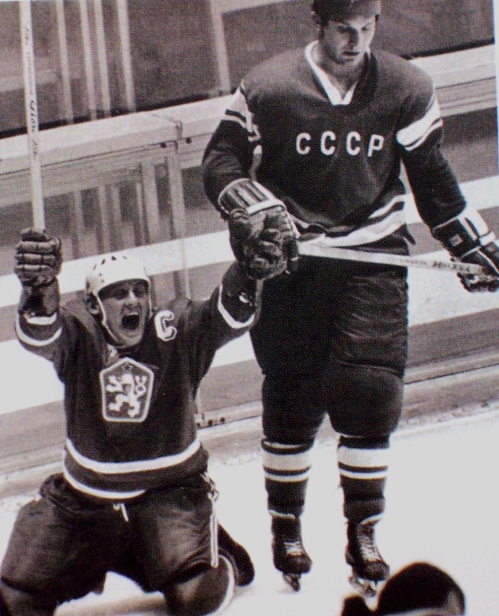 Pamätný záber z olympijského turnaja v Grenoble 1968. Golonka v eufórii po piatom góle kľačí na kolenách, okolo neho korčuľuje smutný silák obrany Sovietov Alexander Ragulin.